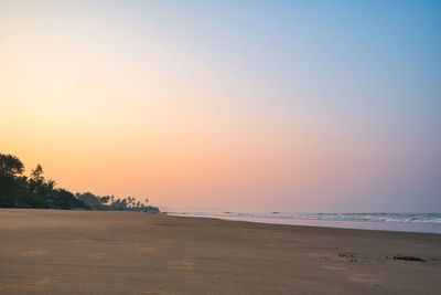 Scenic view of beach against clear sky during sunset