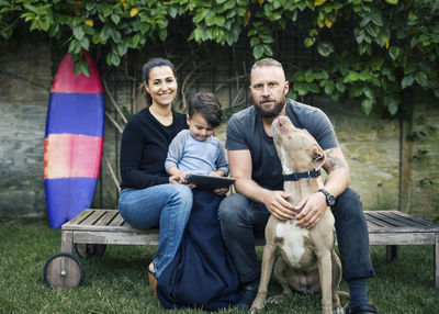 Portrait of family sitting with dog at yard