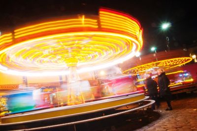 Blurred motion of illuminated carousel against sky at night