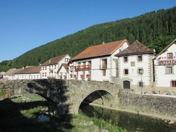 Arch bridge over river amidst buildings against clear sky