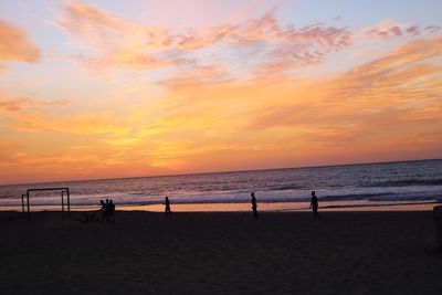 Silhouette people playing on beach against sky during sunset