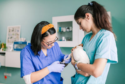 Female veterinarian cutting nails of puppy at clinic