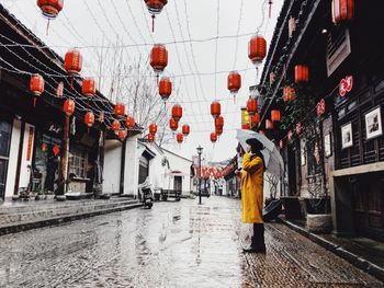 Rear view of man standing on wet road during rainy season