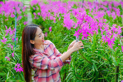 Low angle view of woman with pink flowering plants
