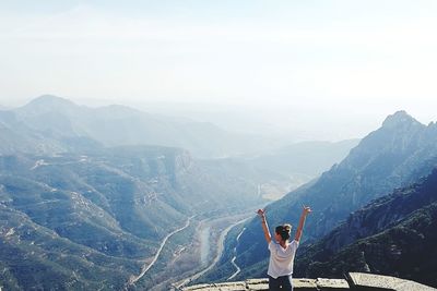 Rear view of person standing on mountain against sky