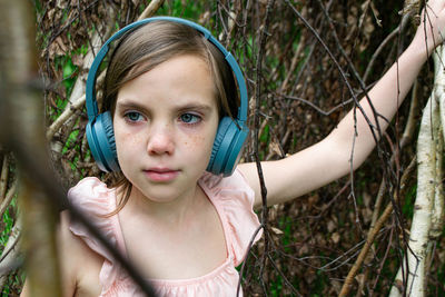 Girl around with a branch and wearing headphones