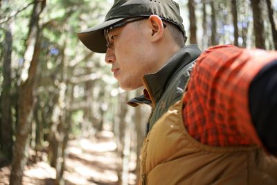 Side view of man standing against trees