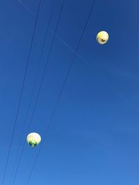 Low angle view of balloons against clear blue sky