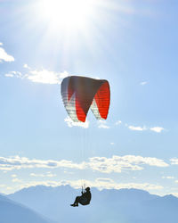 Paraglider flying in blue skies with sunflare