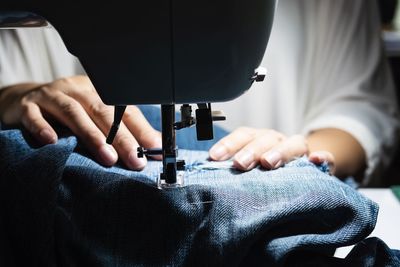 Midsection of woman stitching clothes on sewing machine