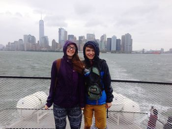 Portrait of young man and woman traveling in boat on hudson river against city