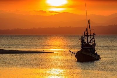 Boat in calm sea at sunset