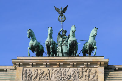 Low angle view of quadriga statue on brandenburg gate against clear blue sky