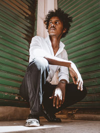 Portrait of young man sitting on wooden wall with the effect of a vintage old film camera 