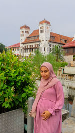 Portrait of woman standing against building