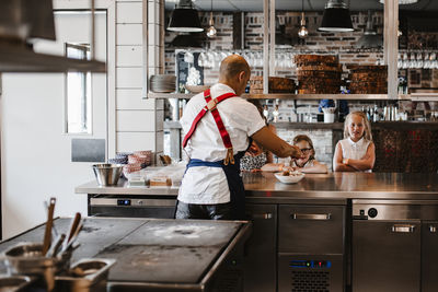 Girls watching chef working in restaurant kitchen