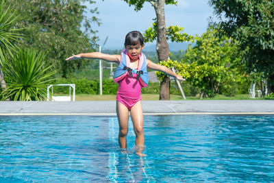 Full length of young woman jumping in swimming pool