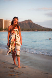 Full length portrait of young woman standing at beach