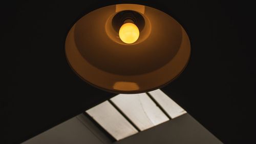 Low angle view of illuminated lamp against black background