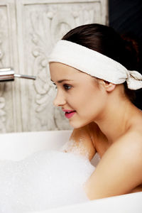 Topless young woman sitting in bathtub at home