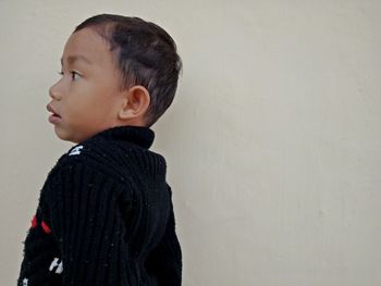 Side view of a boy looking away against wall