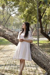 Young woman standing against tree