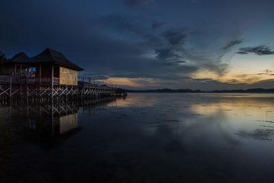 House by sea against sky during sunset