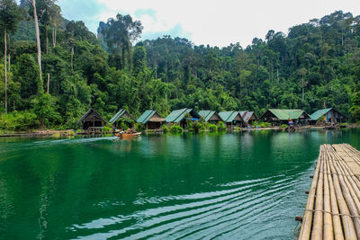 Scenic view of lake by trees and building against sky