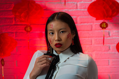 Portrait of beautiful young woman holding red wall