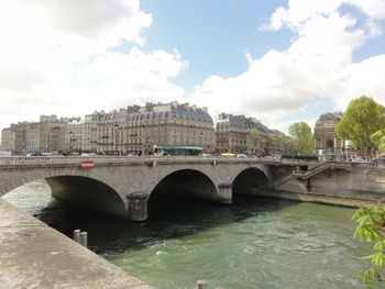 Arch bridge over river against sky in city