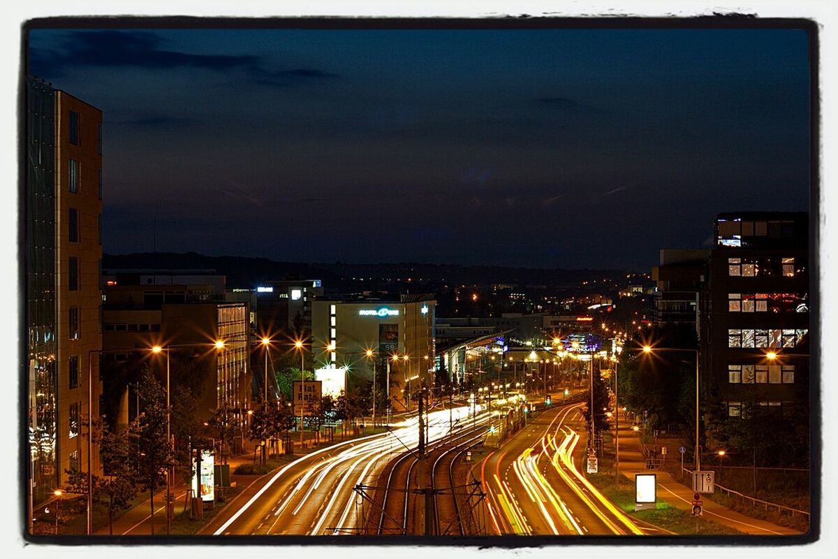 illuminated, night, city, building exterior, transportation, architecture, built structure, sky, road, high angle view, street, cityscape, city life, street light, car, traffic, the way forward, city street, dusk, long exposure