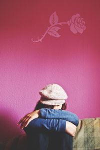 Rear view of woman standing against pink wall