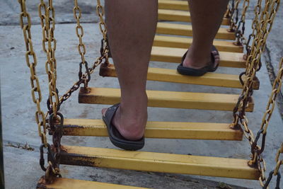 Low section of woman standing on swing