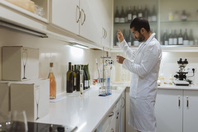 Arabic winemaker working in winelab wearing white gown and gloves.