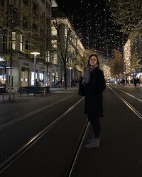 Portrait of woman standing on illuminated city at night