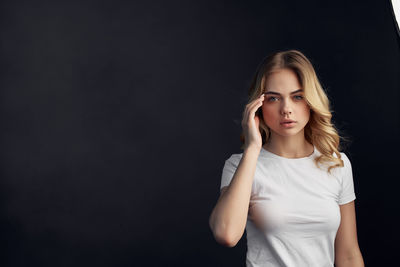 Portrait of young woman against black background