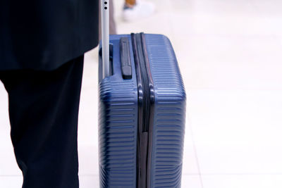 Midsection of man holding suitcase against white background