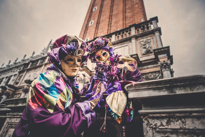 Low angle view of woman holding umbrella against building