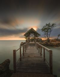 Pier over sea against sky during sunset