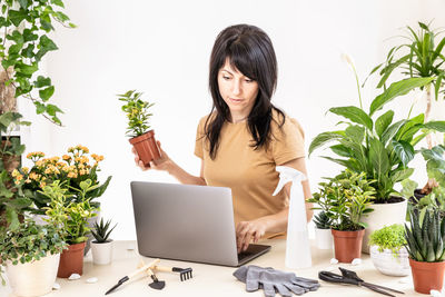 Female gardener using laptop computer at workshop transplantation houseplants