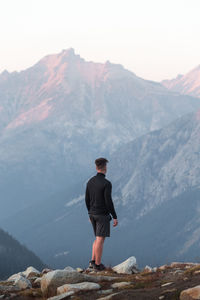 Rear view of man standing on rock against mountain