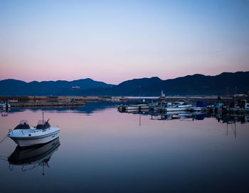 Boats in calm sea at sunset