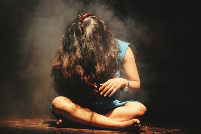 Full length of woman sitting in darkroom