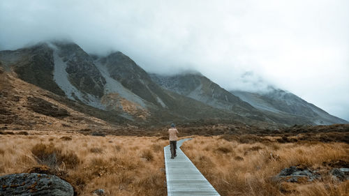 Rear view of man standing on mountain against sky