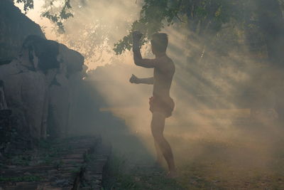 Full length of woman standing by trees during foggy weather