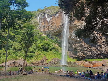 Group of people on rock against waterfall