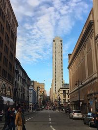 View of city street against cloudy sky