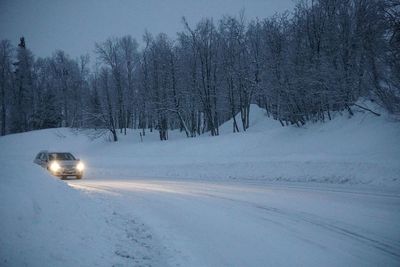 Snow covered car on road against sky