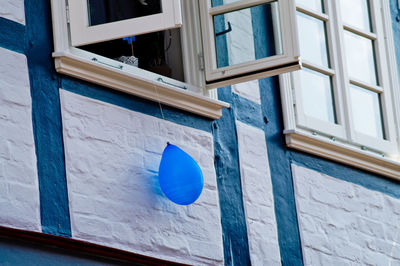 Low angle view of blue balloon hanging from window