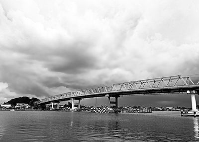 Low angle view of bridge over sea against cloudy sky